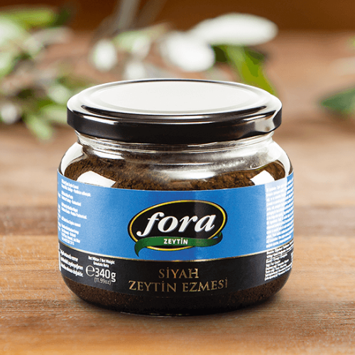 Jar of Fora black olive spread on a wooden surface in a glass jar
