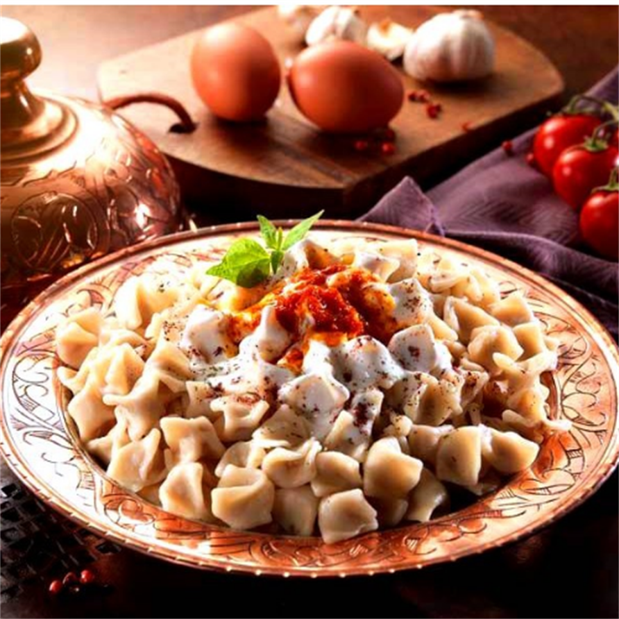 Dish of pasta with a red sauce on a decorative plate, surrounded by ingredients on a wooden board.